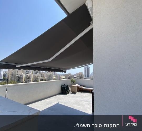 סוכך חיצוני כהה מותקן על קיר מרפסת